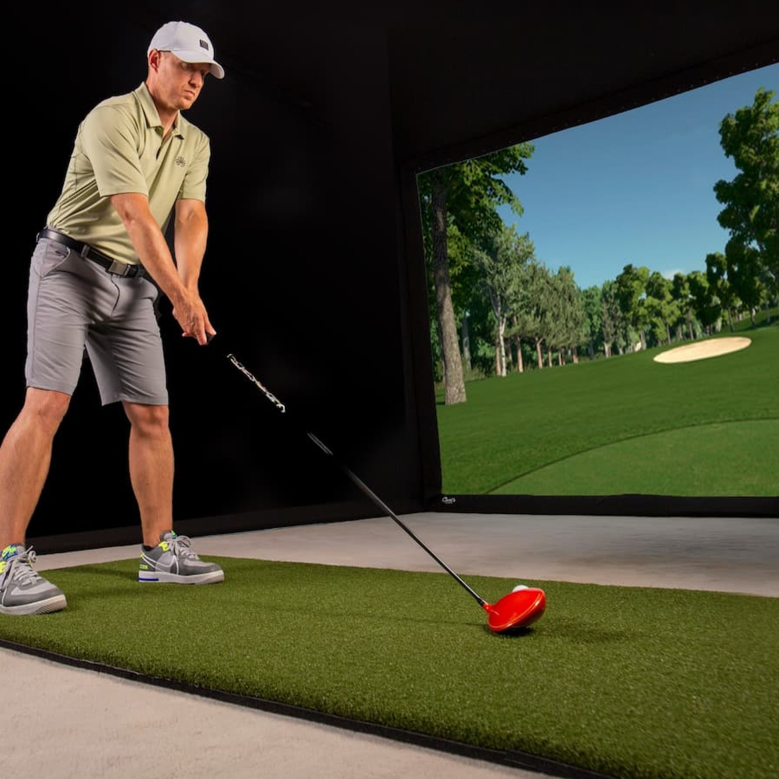 Golfer in Carl's Place Pro Golf Simulator with Premium Impact Screen Material